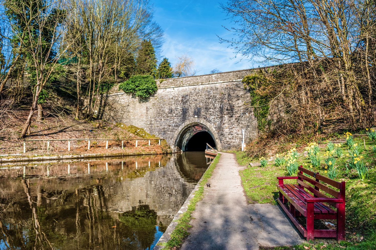 A tunnel entrance on part of the Llangollen canal in North Wales, with reflections in the still water.